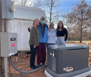 Happy homeowners standing beside their newly installed whole-home Generac generator.