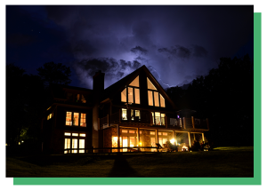 Home illuminated at night with standby generator backup during a severe storm.