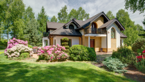 Large two-story home surrounded by trees, green landscaping, and blooming pink flowers.